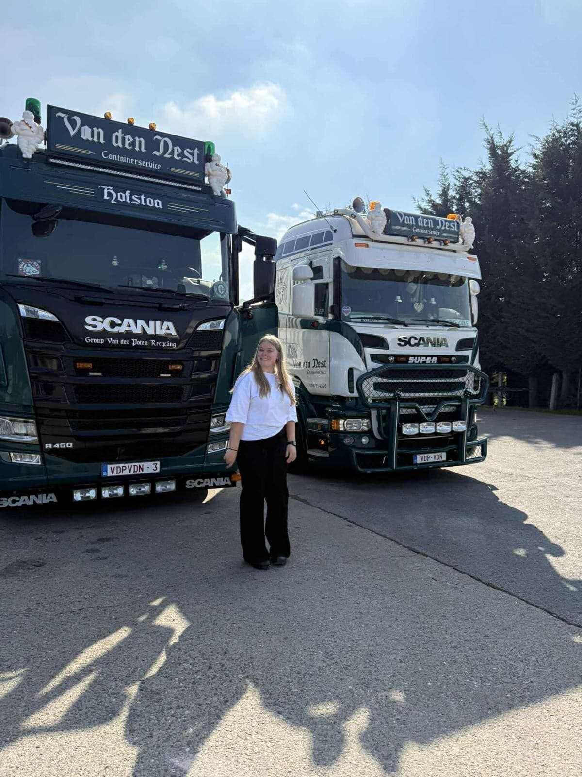 Dieuwke Van der Poten naast twee Van den Nest Scania trucks